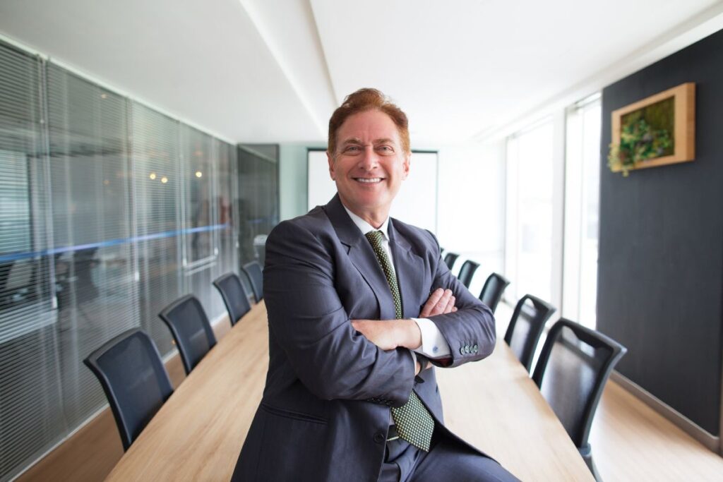 Hombre de negocios sonriendo, sentado sobre la mesa de una sala de juntas